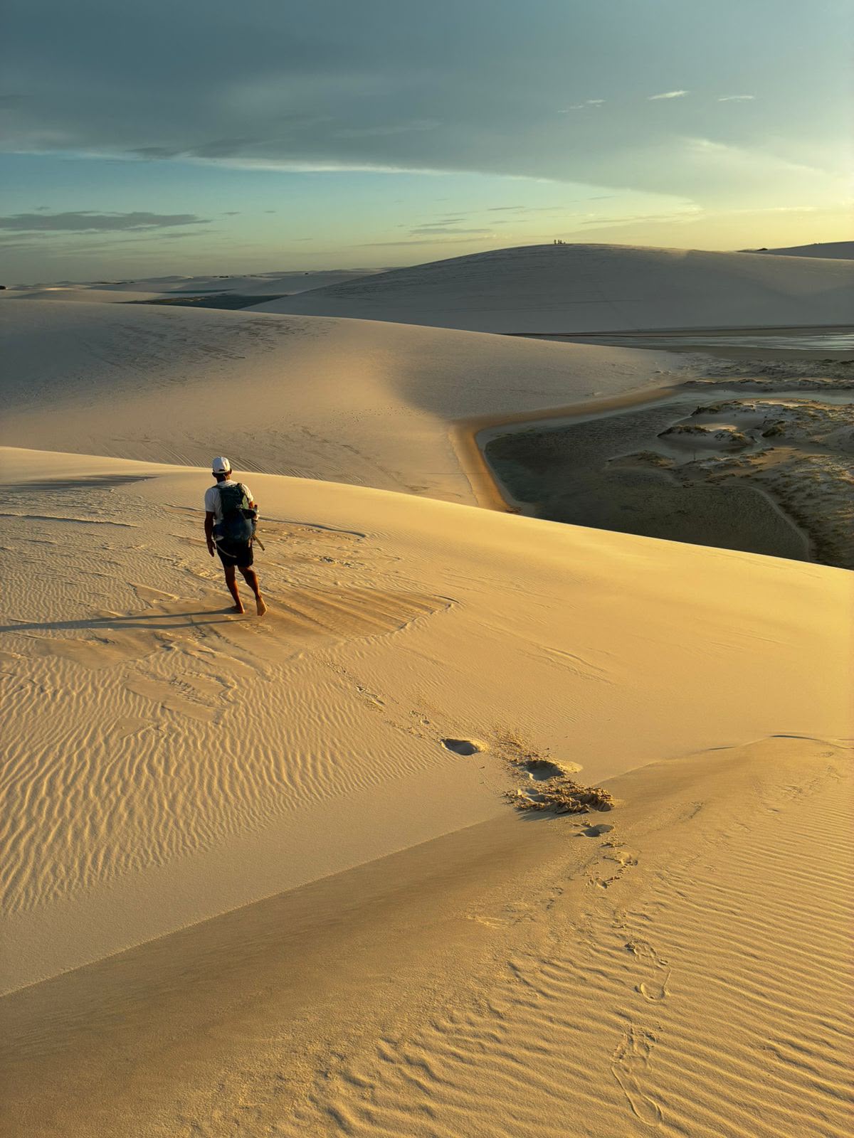 Caminhante no topo de uma duna ao pôr do sol