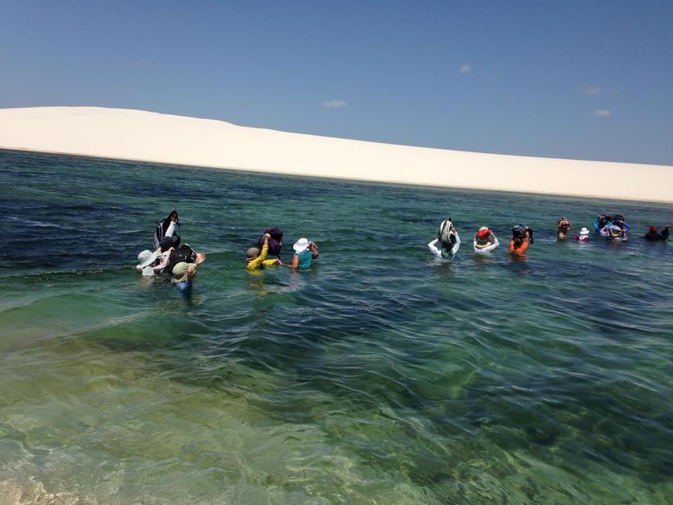 Grupo caminhando ao lado de lagoa azul
