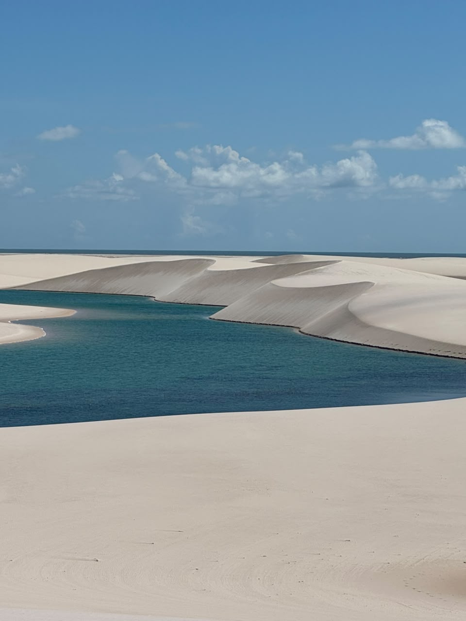 Lagoa azul turquesa entre dunas com o mar ao fundo